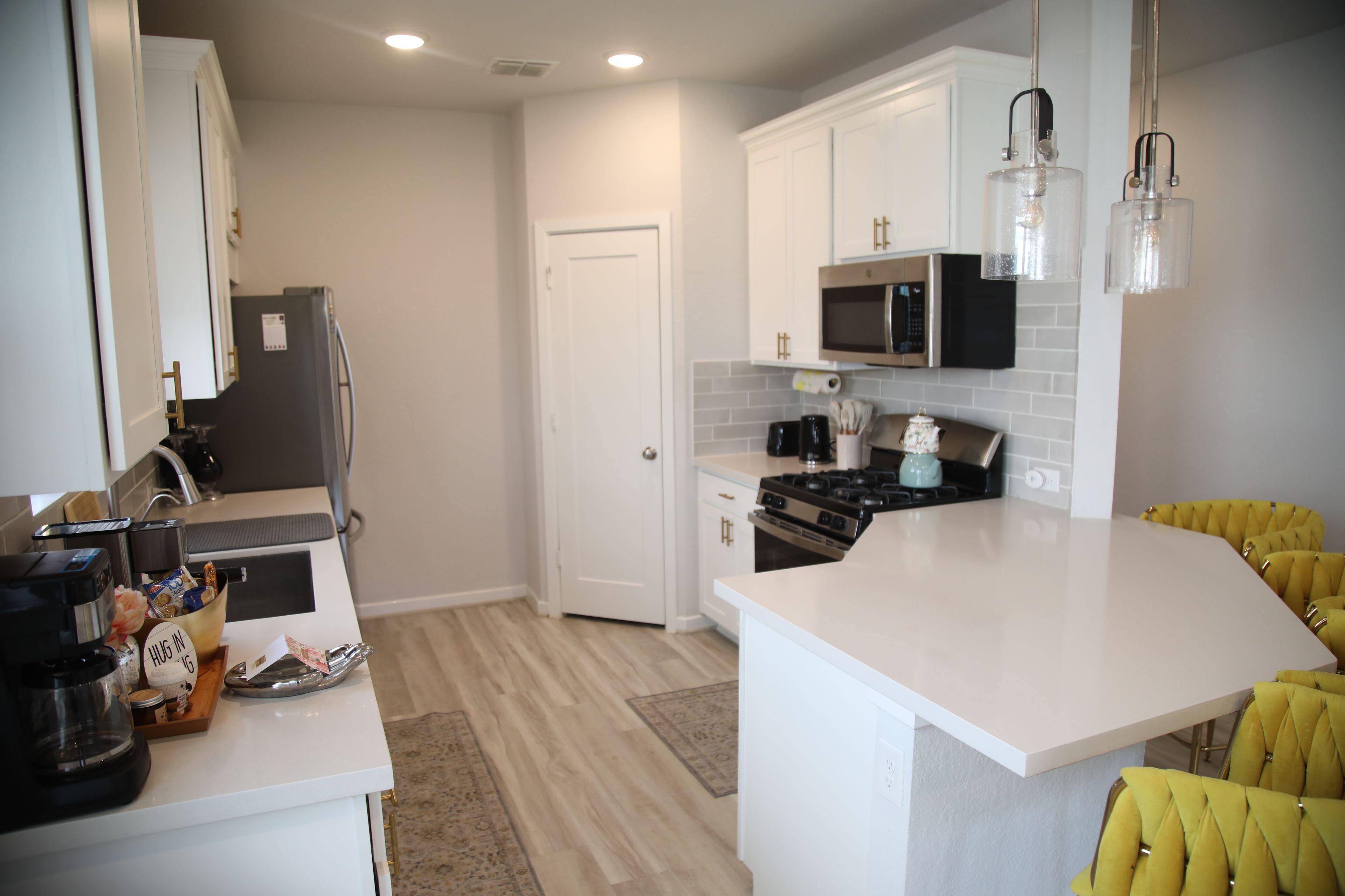 A modern kitchen with white cabinetry, a central island, a microwave, and a stove.