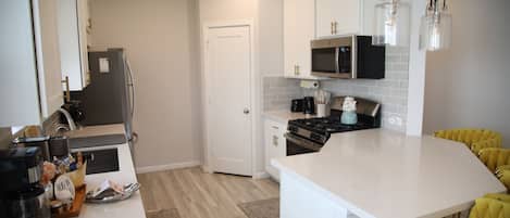 Una cocina moderna con armarios blancos, una isla central, un microondas y una estufa.