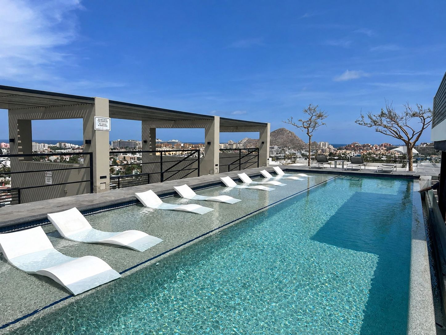 Une piscine dotée de chaises longues et offrant une vue sur le paysage urbain.
