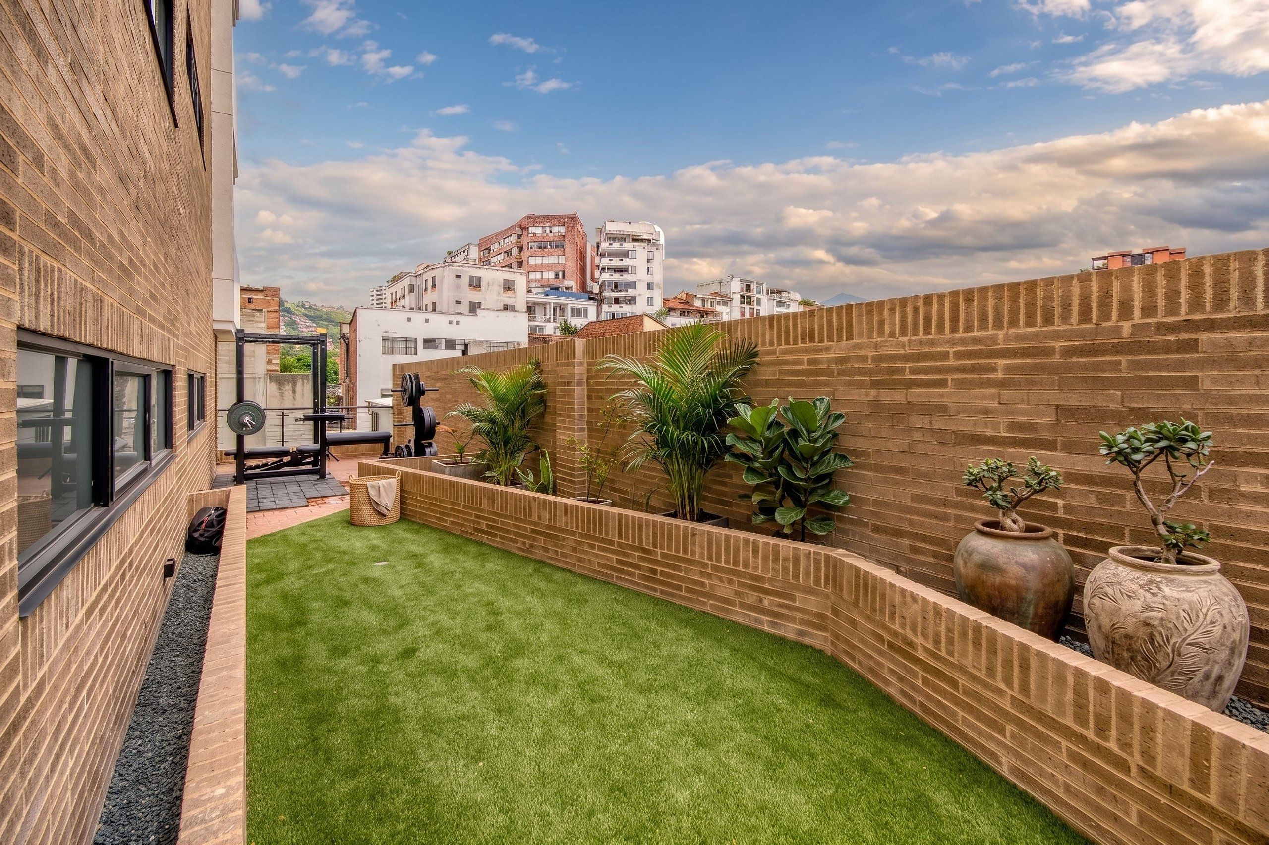 Un patio con césped, paredes de ladrillo y plantas en macetas.