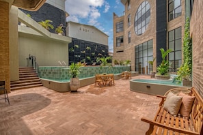 Una terraza en la azotea con piscina, zonas de estar y una escalera que lleva a un nivel superior.