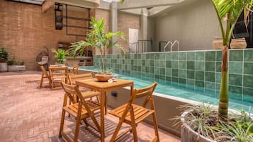 A pool area with wooden furniture and potted plants.