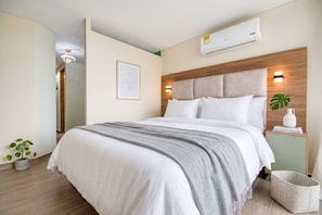 A modern bedroom with a bed, bedside tables, an air conditioner, and a wall-mounted light fixture. - Edificio Vita Habitare (Cali)