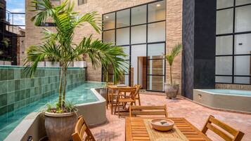An outdoor patio with a pool, wooden furniture, and potted plants.
