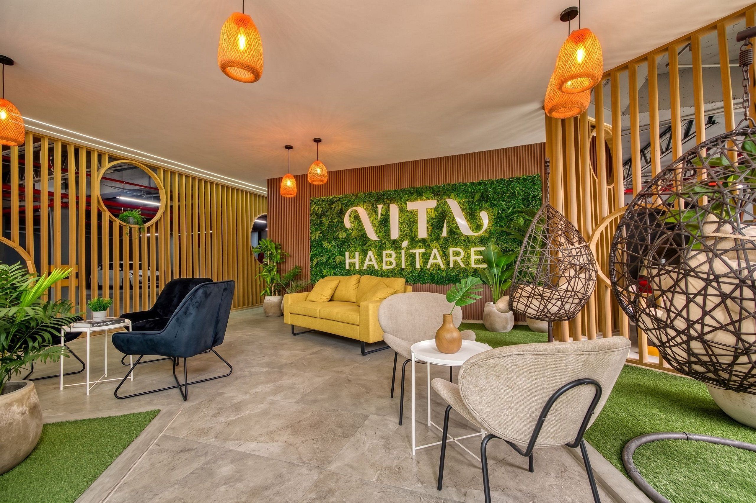 A modern interior with a sofa, chairs, and a wall with greenery and a sign.