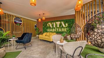 A modern interior with a sofa, chairs, and a wall with greenery and a sign.