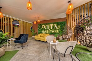 Un interior moderno con un sofá, sillas y una pared con plantas y un letrero.