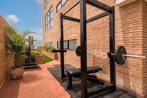 Zona de pesas con un rack para sentadillas, banco y barras.