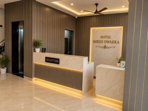 A hotel reception area with a marble reception desk, a reception sign, and a wall-mounted sign for 'HOTEL SHREE DWARKA'. - Hotel Shree Dwarka Devbhumi Dwarka (Dwarka)
