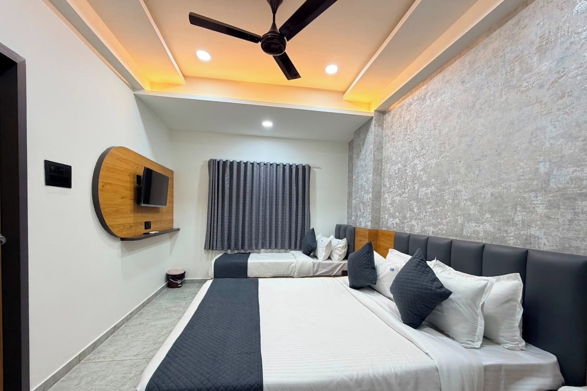 A hotel room with two beds, a ceiling fan, a flat-screen TV, and a large window with curtains.