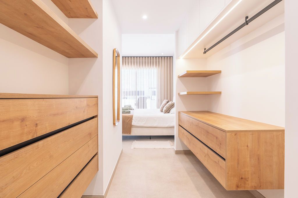 A narrow hallway with wooden storage units on either side and a bed at the end.