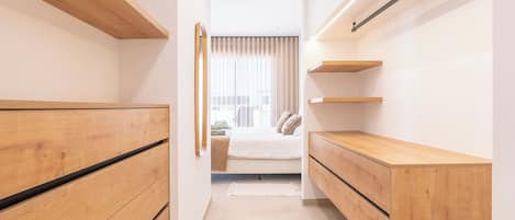 A narrow hallway with wooden storage units on either side and a bed at the end.