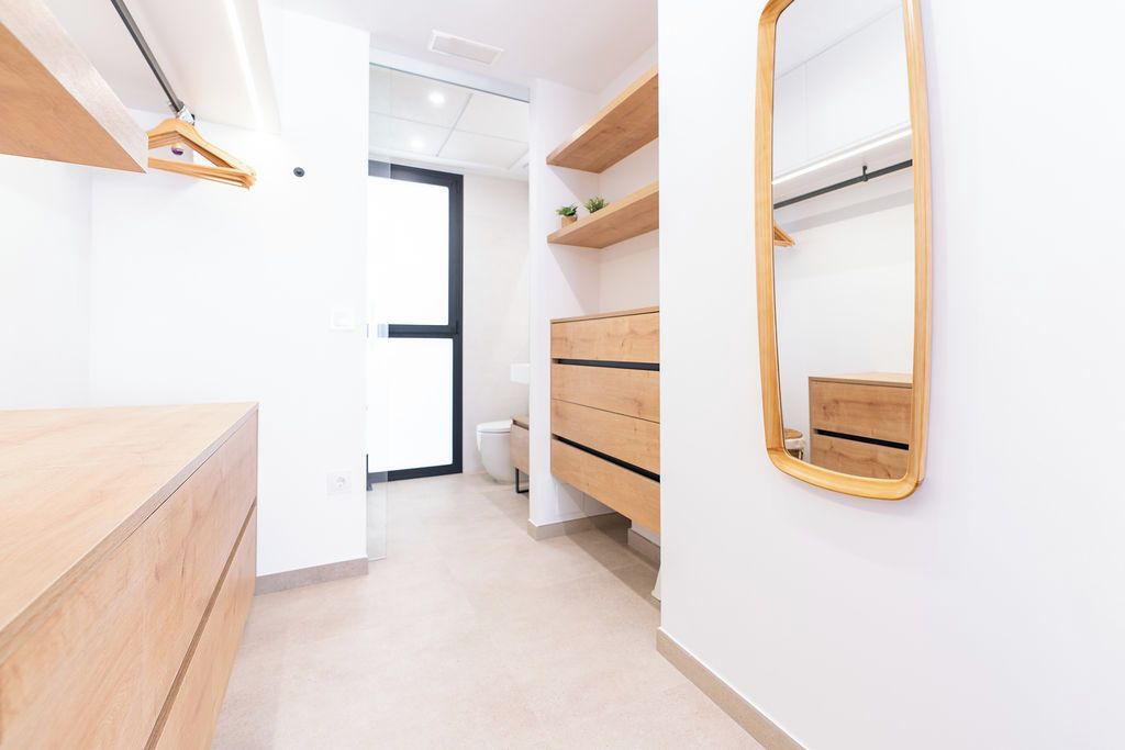 Un baño moderno con tocador de madera, espejo y inodoro.