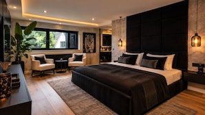 A modern bedroom with a large bed, bedside tables, a sofa, and a potted plant.