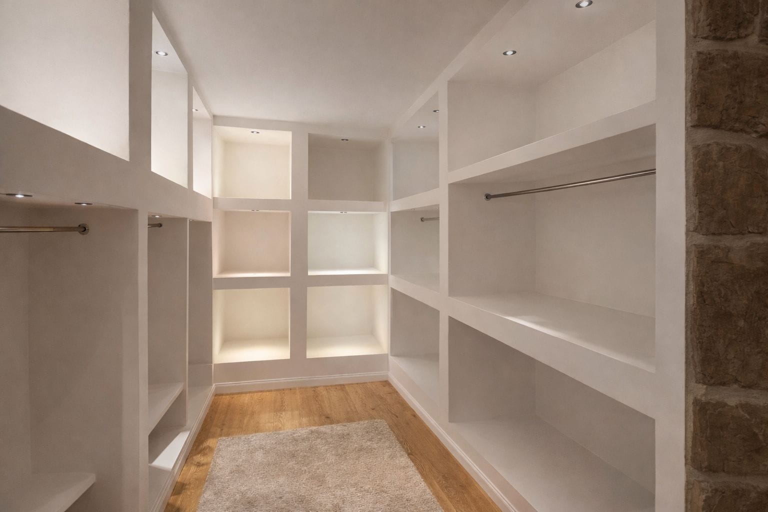 Un vestidor amplio con varias repisas y piso de madera.