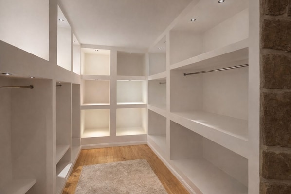 A walk-in closet with multiple shelves and a wooden floor.