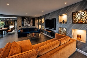 A modern living room with a large sofa, a coffee table, and a flat-screen TV.