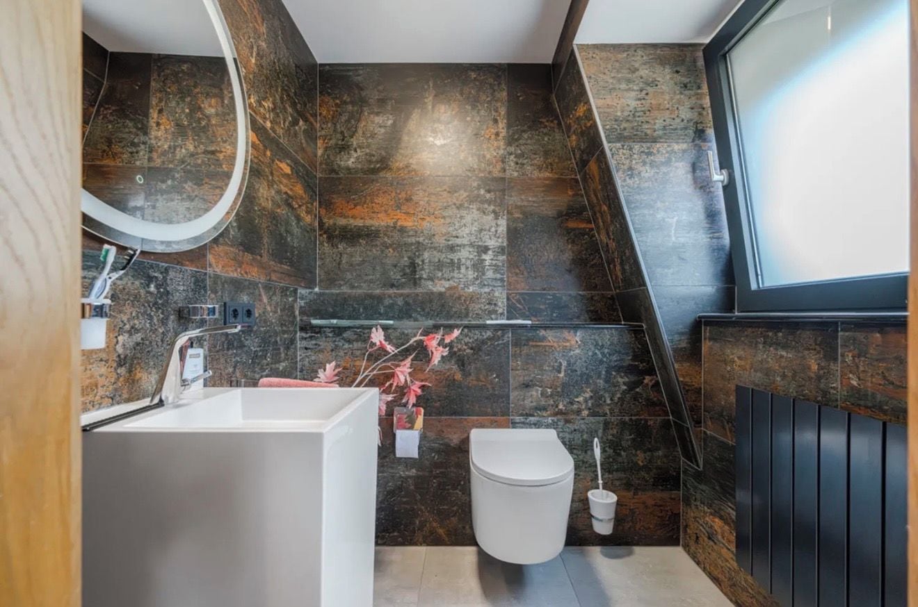Een moderne badkamer met een witte badkuip, toilet en douche.