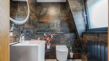 Een moderne badkamer met een witte badkuip, toilet en douche.