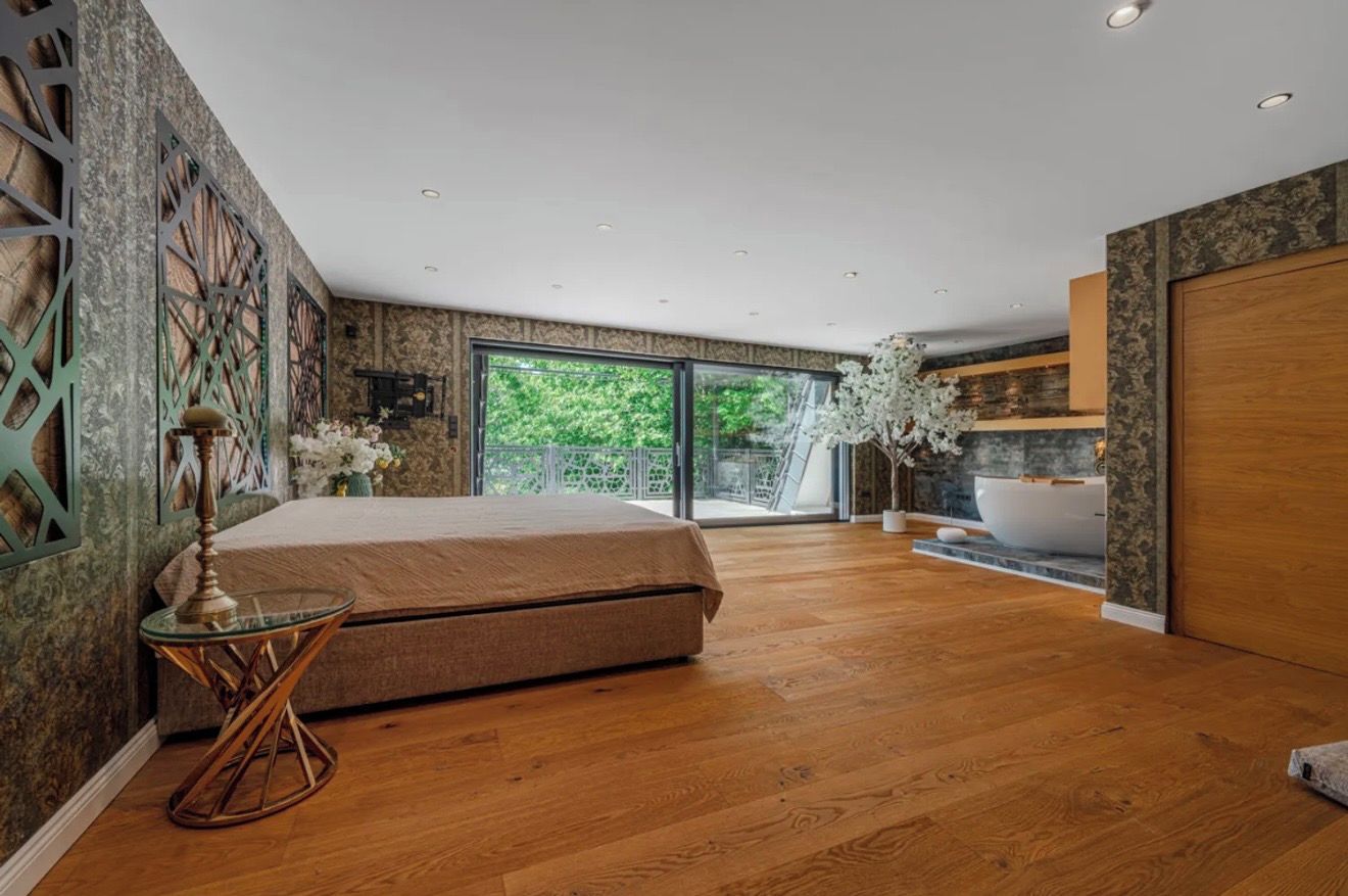 A modern bedroom with a large bed, a glass table, and a bathtub.