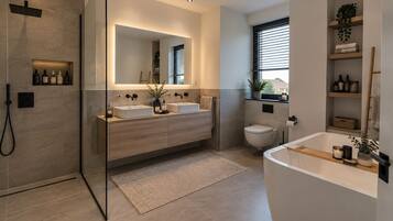 Un baño moderno con ducha envuelta en vidrio, tocador doble, inodoro y bañera.
