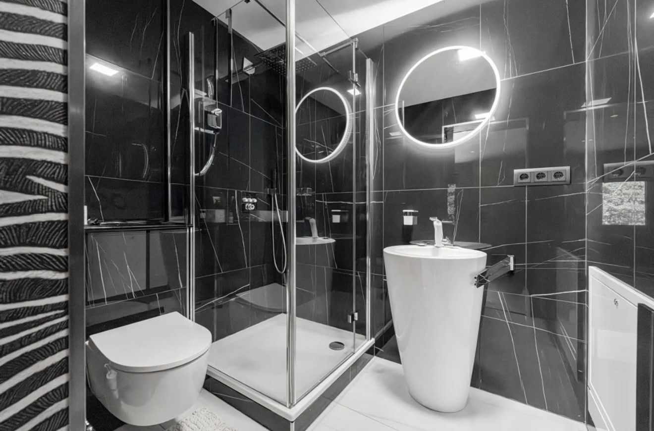 A modern bathroom with a glass-enclosed shower, a toilet, and a large sink.