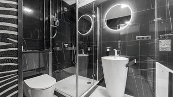 A modern bathroom with a glass-enclosed shower, a toilet, and a large sink.