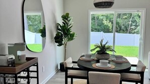 A dining area with a round table, chairs, a hanging light fixture, and a large mirror on the wall. - Modern Stay w/ 2 King Beds | Near Elon & Downtown (Graham)