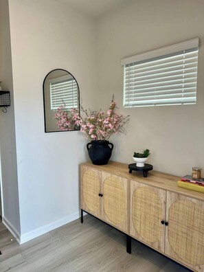 A room with a wooden cabinet, a mirror, and a potted plant.