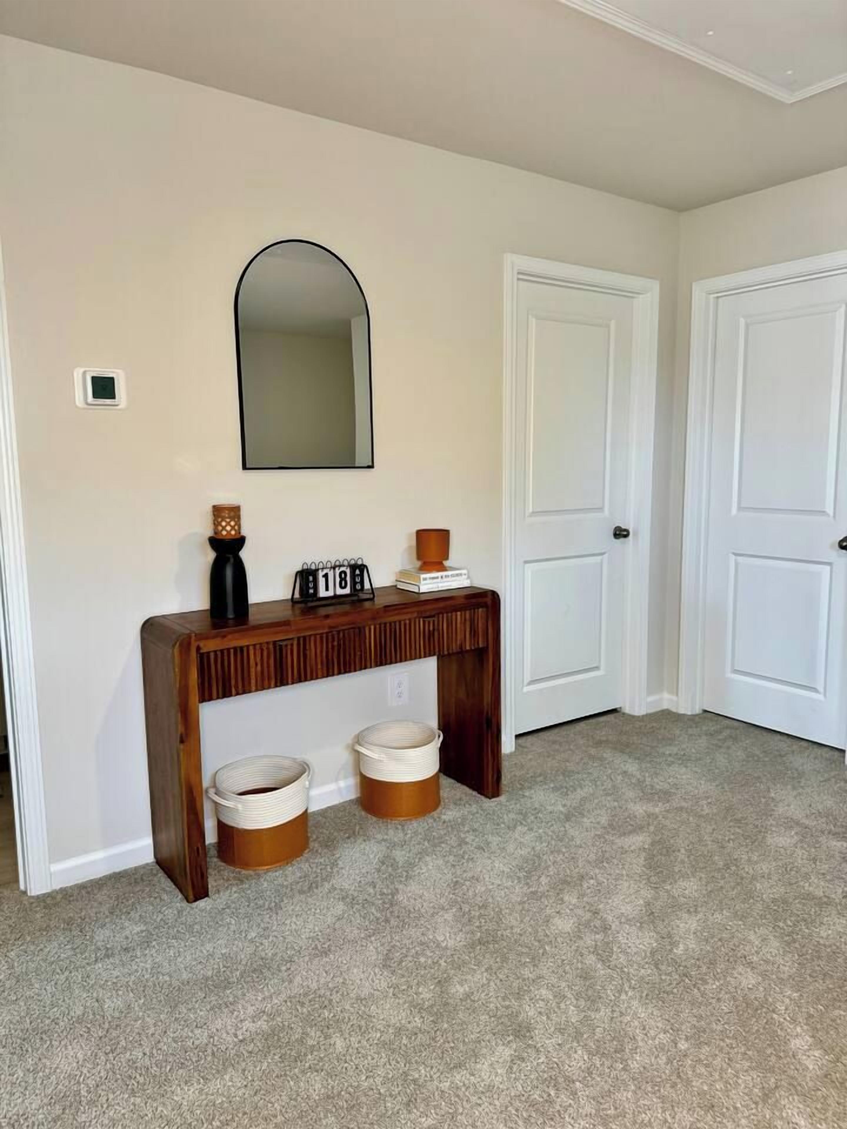 A hallway with a wooden console table, a mirror, and two doors.