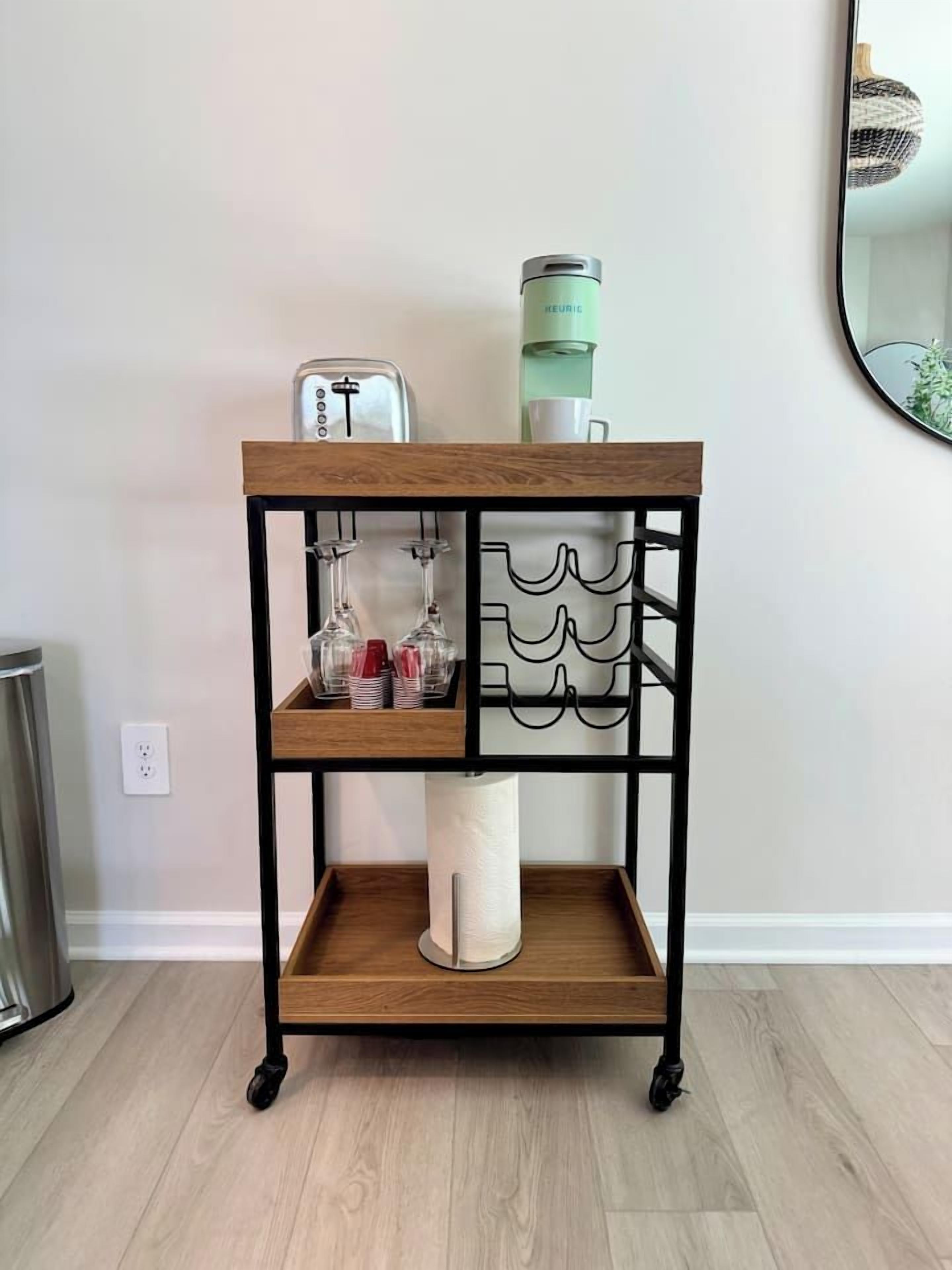 A wooden and metal coffee station with a kettle, cups, and glasses.