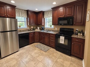 A kitchen with wooden cabinets, stainless steel appliances, and a patterned rug. - Cascade Hollow Cottage Next to Dickel Distillery (Normandy)