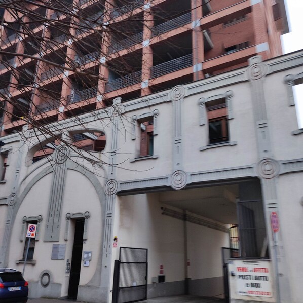 Ein Gebäude mit großem Bogenportal, zahlreichen Fenstern und einem Schild, das einen Parkplatz kennzeichnet.
