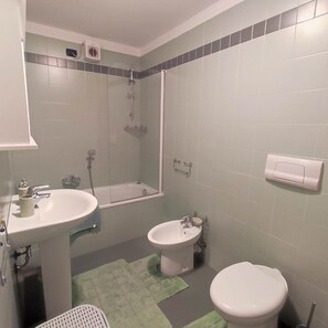 Ein Badezimmer mit Waschbecken, Bidet, Toilette und Duschbereich.