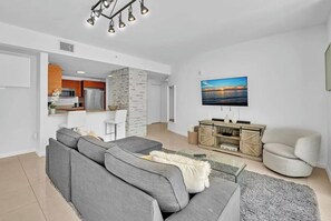 Ein modernes Wohnzimmer mit einem grauen Ecksofa, einem flachbildfernseher an der Wand und einer Wand mit Steinverkleidung.