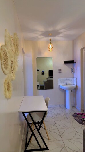 A compact kitchen with a white sink, a small table, and a chair. - Thika road 1 bedroom executive  Airbnb unit located off Thika road at exit 12 (Ruiru)