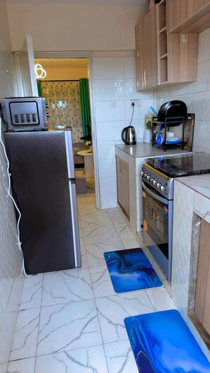 A compact kitchen with a refrigerator, stove, and various kitchenware. - Thika road 1 bedroom executive  Airbnb unit located off Thika road at exit 12 (Ruiru)