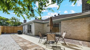 Un espace patio avec une table et des chaises, un parasol et un mur en briques.