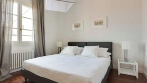 Een hotelkamer met een bed, twee nachtkastjes, een raam met gordijnen en een radiator.