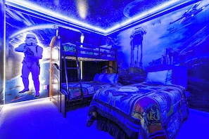Habitació amb llits superposats, un mural temàtic de Star Wars i una il·luminació ambientada a l'espai.