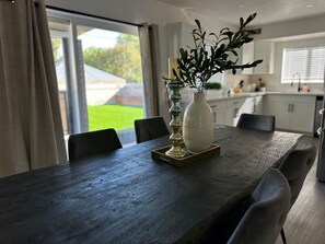 A dining table with chairs, a vase with greenery, and a decorative candle holder. - Terrific 6-bedroom house with AC in vibrant Las Vegas 10 minutes from the Strip. (Las Vegas)