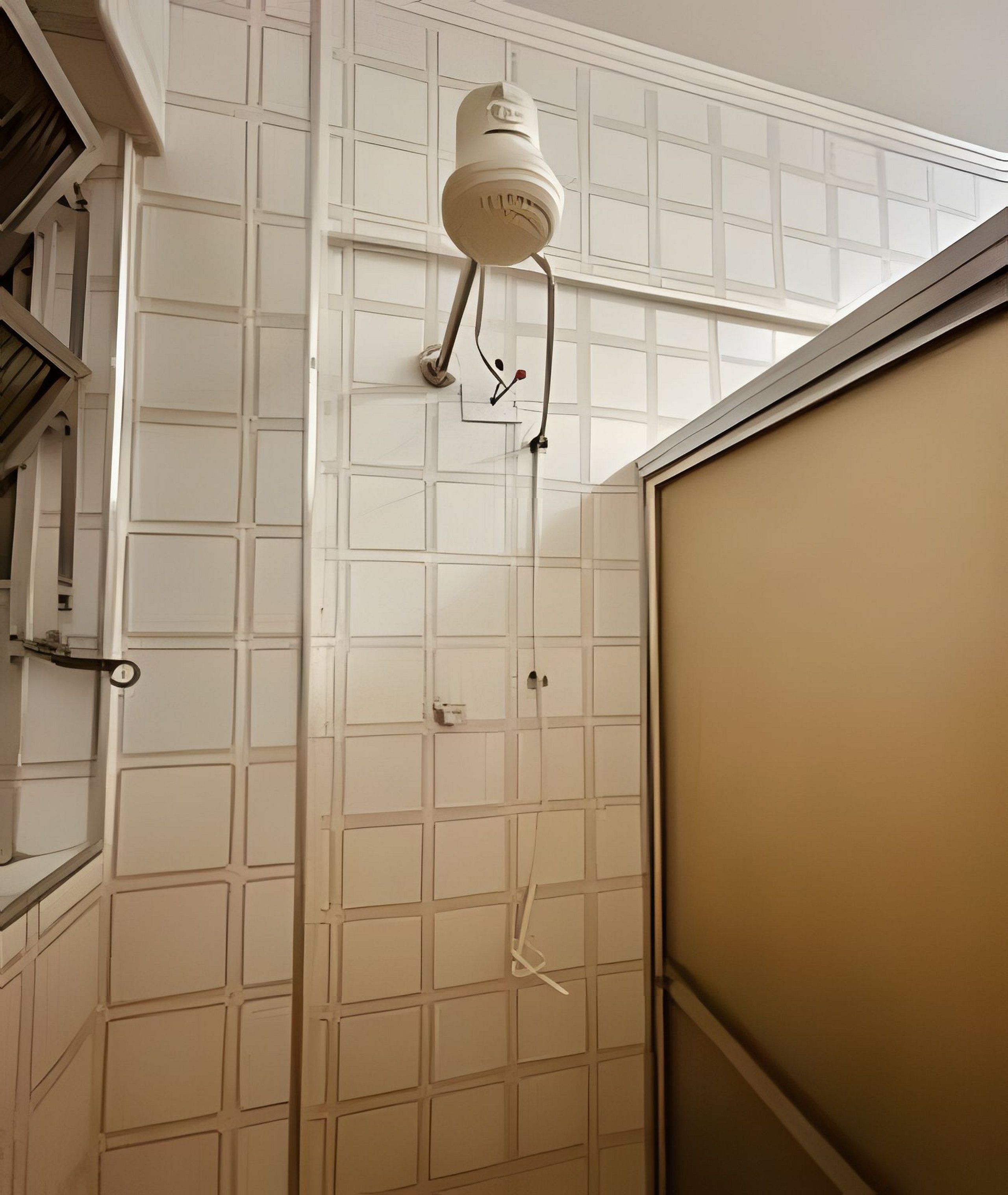 Un baño con pared de azulejos blancos, zona de ducha y una puerta.