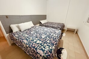 A bedroom with two beds, a small bedside table, and a wall socket.