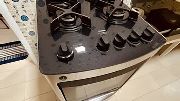 Una cocina con estufa a gas, azulejos blancos y un salpicadero decorado.
