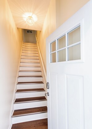 A staircase with wooden steps leading to a white door with a frosted glass panel. - Second-floor 2BR above Clifton's restaurant row | Stained glass, high ceilings | Rain shower, 750 Mbps | Walk everywhere (Louisville)