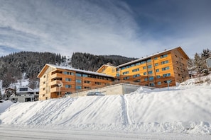 A modern hotel with multiple floors and balconies, situated on a snowy slope with a forested mountain backdrop. - Wifi, ski-in/ski-out & foot of the slopes, fitness, sauna, hammam, tv, ski locker, 35-39m², Vercorin (Vercorin)