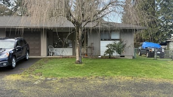 Een woonhuis met garage, oprit, gazon en een boom.