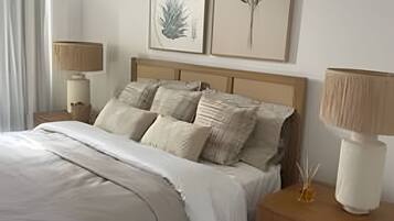 Un dormitorio con cama, dos mesitas de noche y dos lámparas de pared.