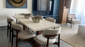 A modern dining area with a long table, chairs, and pendant lights. - The Penthouse at Vista Alta (Punta Cana)