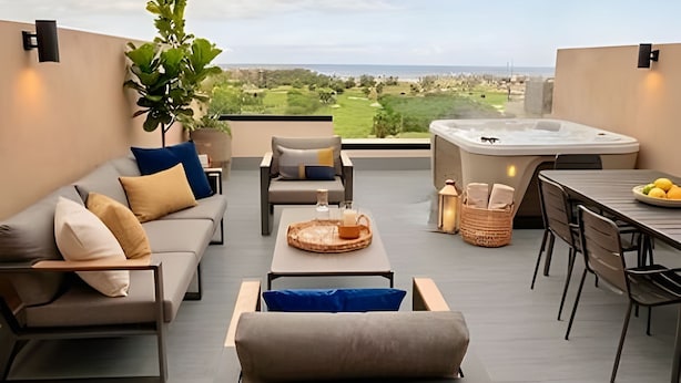 A modern outdoor seating area with a hot tub, a dining table, and a view of the landscape. - The Penthouse at Vista Alta (Punta Cana)